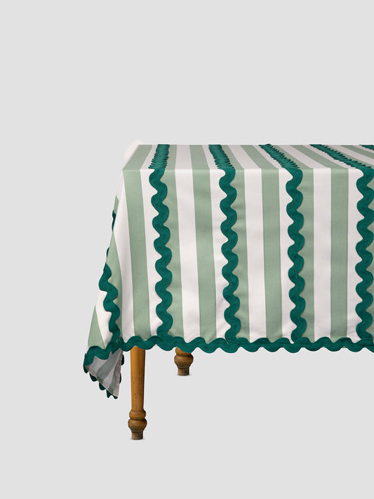 Green and white striped tablecloth with green trimming placed on a table