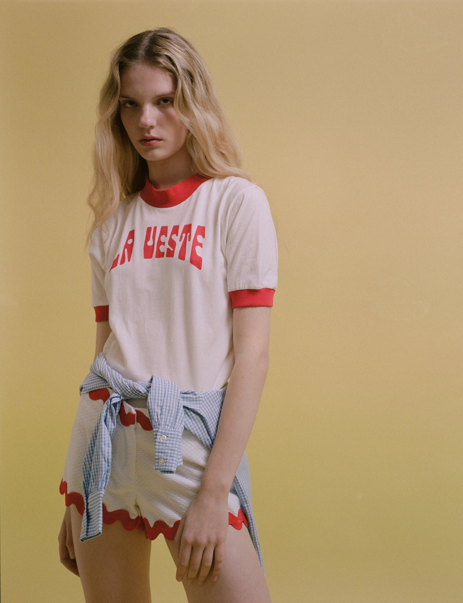 Model wearing a vintage La Veste logo shirt and white shorts with red trim.