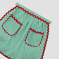Green vichy quilted apron with red piping detail and two matching pockets on the front.