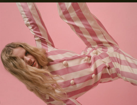 Model posing in pink and white striped pajamas.