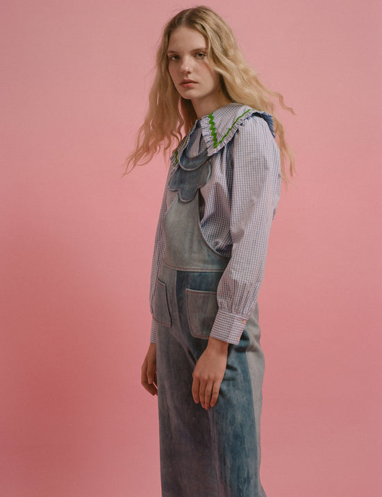 Woman in denim overalls and long sleeve striped shirt with collar detailing