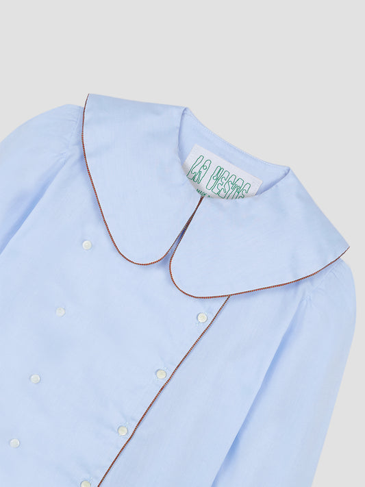 Women's long-sleeved blue shirt with brown piping details and white button front closure