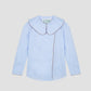 Augusta Shirt Celeste is a blue long sleeve shirt with brown piping details and white button closure.