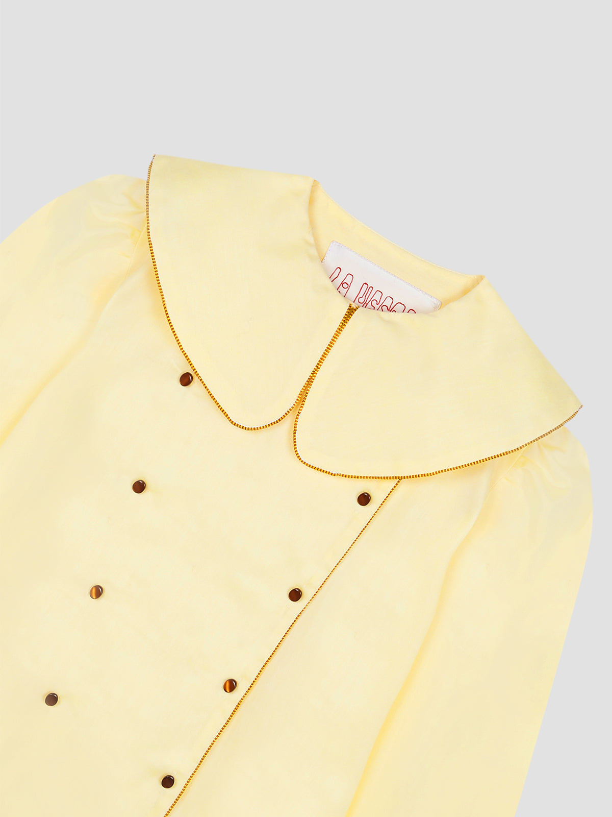 Women's yellow long sleeve shirt with brown piping details on collar and sleeves