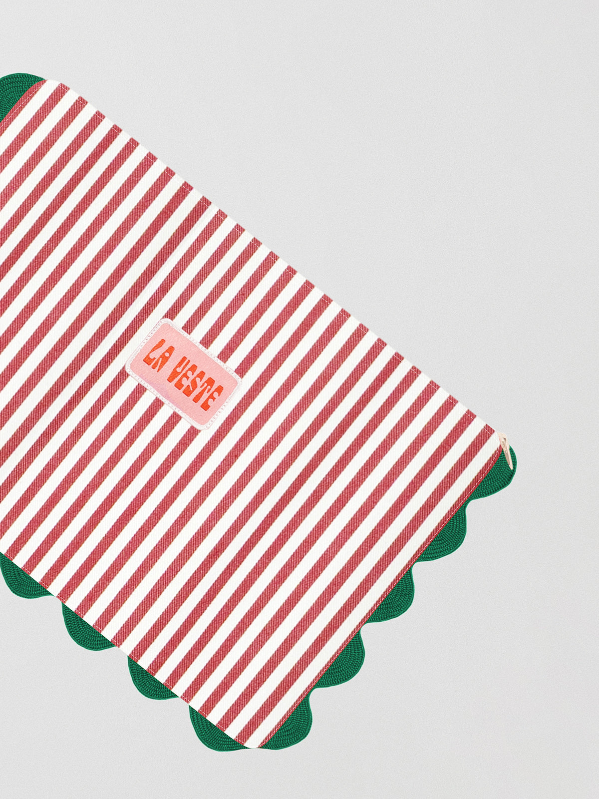 Red and white striped toiletry bag with zipper closure and green piping details all around the edge