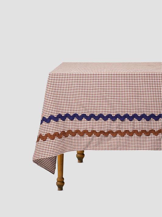 Dining table with a brown vichy check tablecloth and matching blue and brown trim.
