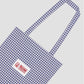 Blue checkered canvas tote bag with La Veste logo at the top center