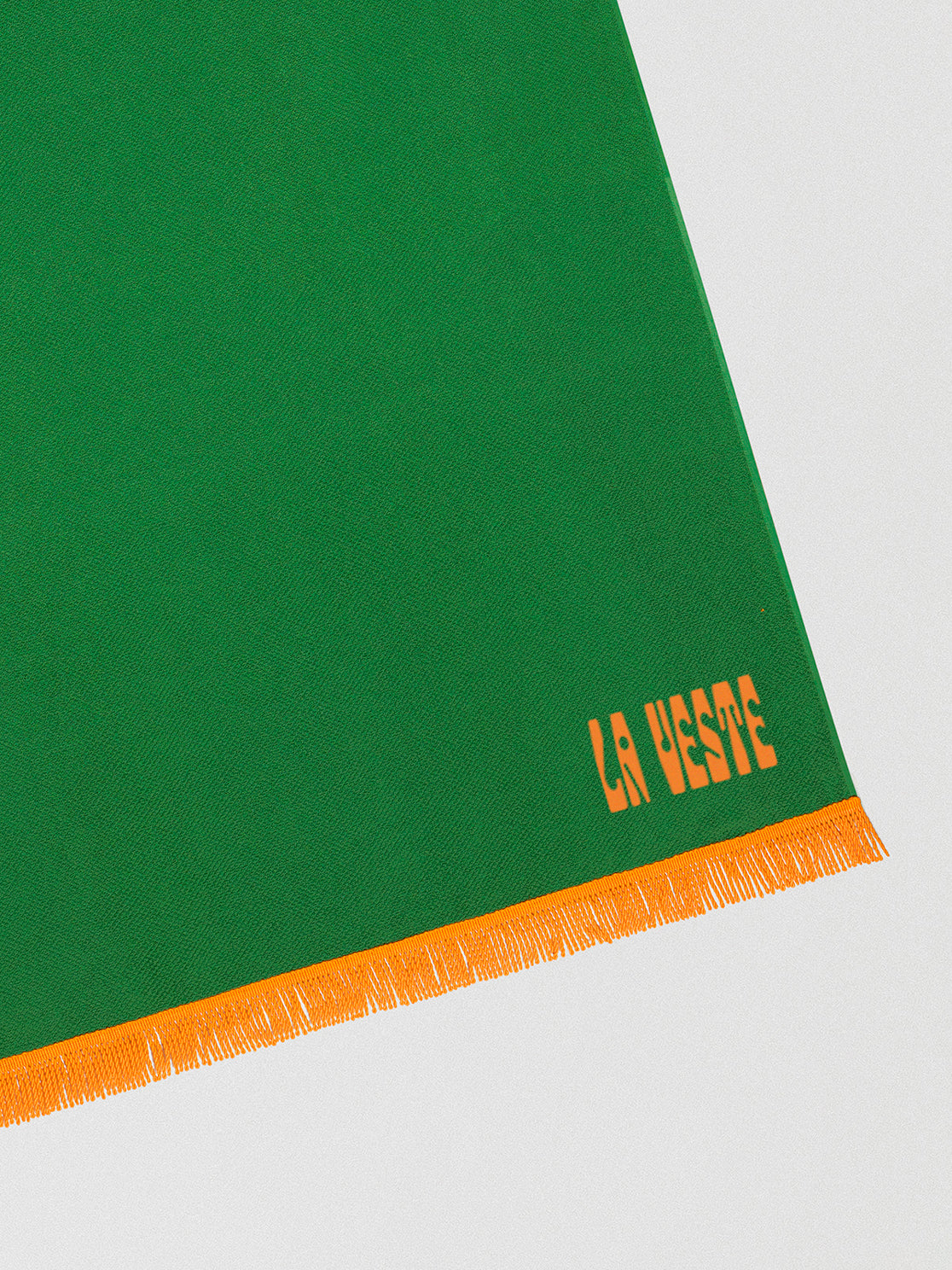 Towel made in green cotton with orange fringes detail. 