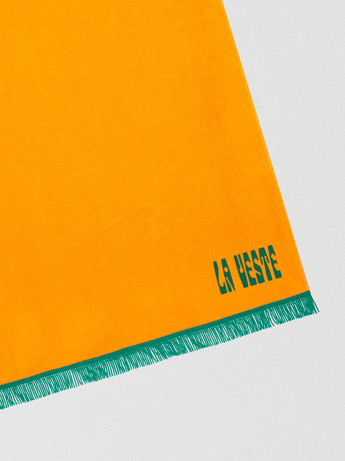 Towel made in orange cotton with green fringes detail. 