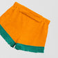 Towel shorts made in orange cotton with green fringes. 